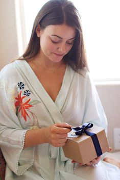 a woman in a robe holding a gift box