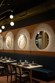 an empty restaurant with round mirrors on the wall and blue banquet tables in front of them