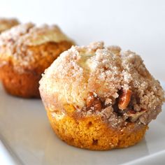 two muffins with powdered sugar on top are sitting on a white plate