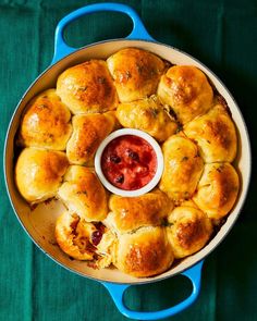 a blue pan filled with rolls covered in cheese and sauce