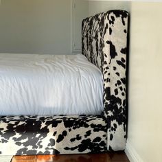 a cow print upholstered bed with white sheets and black and white headboard