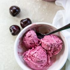 a bowl filled with ice cream next to some cherries