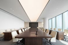 an empty conference room with white chairs and wooden table