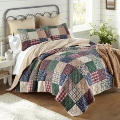 a bedroom with a bed covered in a multicolored patchwork quilt and pillows