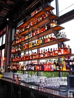 many bottles and glasses are lined up on the bar