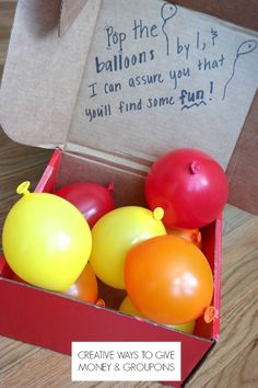 an open box filled with balloons on top of a wooden table