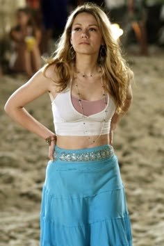 a woman standing on top of a sandy beach next to a blue frisbee