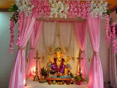 a decorated stage with pink drapes and white flowers on the ceiling, gandap draped over it