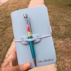 a person holding a blue notebook with a pen attached to it