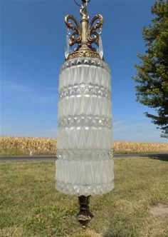 a tall glass vase sitting on top of a grass covered field