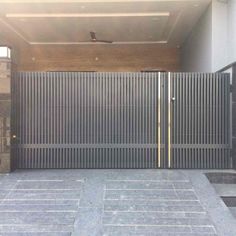 an open gate in front of a building with stone flooring and brick walkways