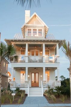 a white two story house with palm trees in front