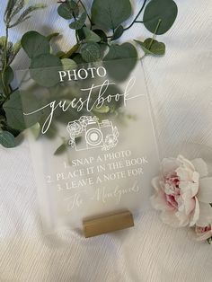 a photo guest book next to flowers on a white sheet with greenery in the background