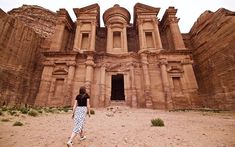 a woman standing in front of an ancient building