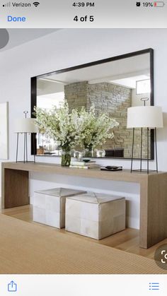 a large mirror sitting on top of a wooden table next to a vase filled with flowers