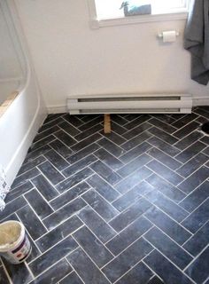 a bathroom with black and white tile flooring next to a bathtub in the corner