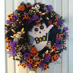 a wreath decorated with halloween decorations on the front door to celebrate boo's day