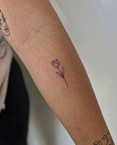 a woman's arm with tattoos and a single flower on the left side of her arm