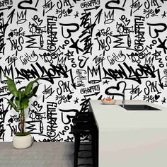 a kitchen with black and white graffiti on the wall next to a plant in a pot