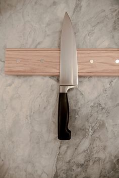 a knife hanging on the wall with a wooden handle