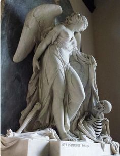 an angel statue with a skeleton sitting next to it