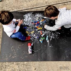 two young boys are playing with legos on the ground