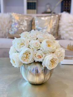 a vase filled with white flowers sitting on top of a table next to a couch