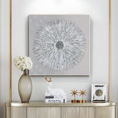 a vase with flowers sitting on top of a wooden cabinet next to a painting and framed pictures