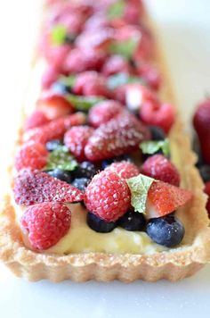 there is a pastry with berries on it and other fruit in the middle, along with raspberries