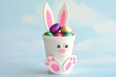 a cup filled with easter eggs and bunny ears