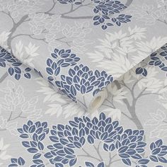 a blue and white flowered wallpaper with leaves on it's side, next to a roll of tape