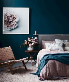 a bedroom with blue walls and pink bedding, two chairs and a painting on the wall