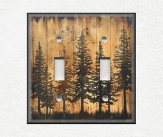 two light switch covers with trees painted on the wood and metal inserts in between them