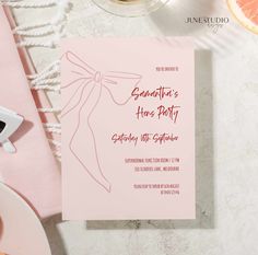 a pink party card with a bow on the front, and an orange slice next to it