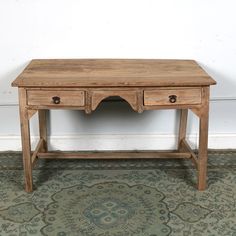 an old wooden table with two drawers on it's legs, against a white wall