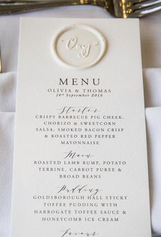 a white menu card sitting on top of a table next to a fork and knife