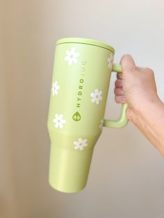 a person holding a green coffee cup with white flowers on it