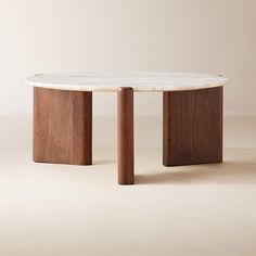 a marble top coffee table with two wooden legs and an oval shaped base, on a beige background