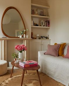 a living room with a couch, mirror and flowers on the coffee table in front of it