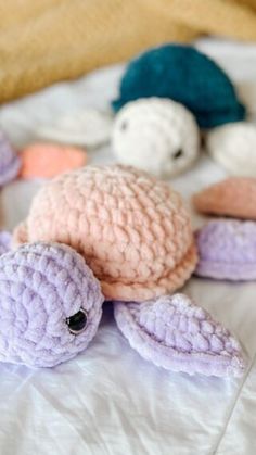 several stuffed animals are laying on a white bed sheet with one turtle in the middle