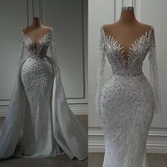 a white wedding dress with long sleeves and an open back, on display in front of a mirror