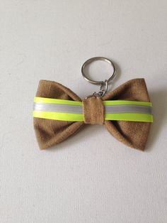 a brown bow tie keychain with yellow and gray stripes on it's side