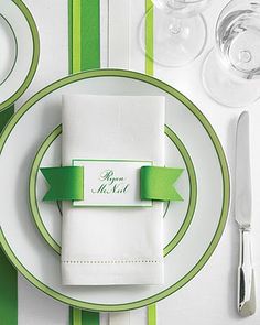 a place setting with green and white striped table cloths, napkins and silverware