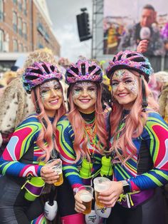 two women in colorful costumes are holding beers