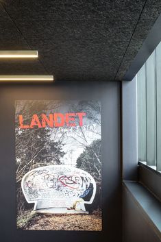 a large poster on the wall next to a window in a room with black walls