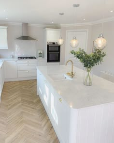 a large kitchen with white cabinets and wood flooring on the walls, along with an island in the middle