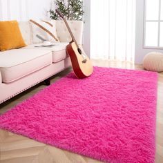 a bright pink area rug with a guitar on it in front of a white couch