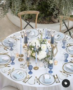 a white table topped with blue and gold place settings