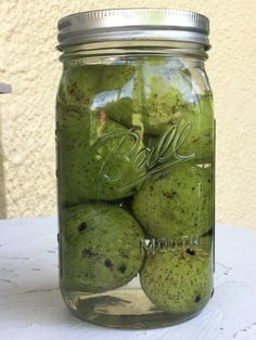 a jar filled with green fruit sitting on top of a table