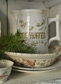 a white pitcher sitting on top of a counter next to two bowls and saucers